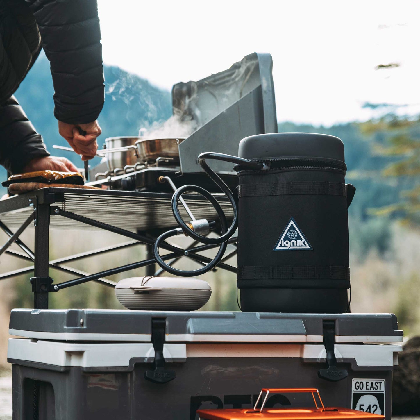 Gas growler with black insulated case and connected hose on outdoor grill setup