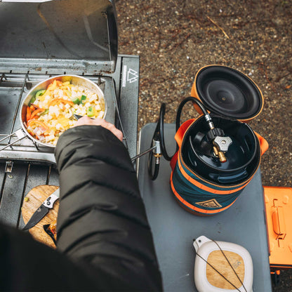 Gas growler with open insulated case and hose on outdoor vehicle grill