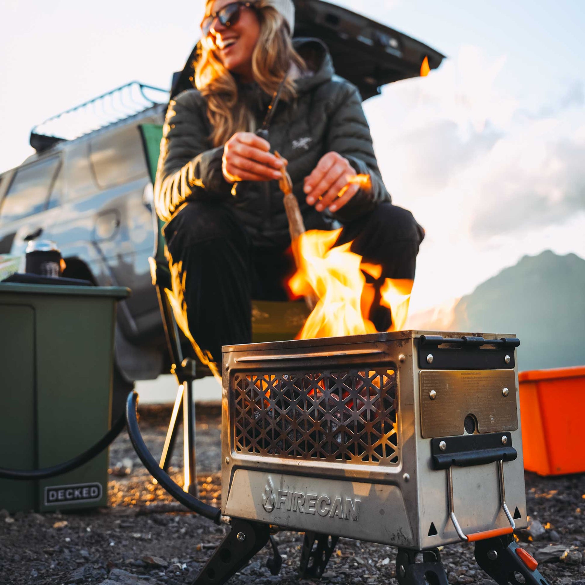 Orange portable fire pit showing steel mesh firebox with flames and control panel