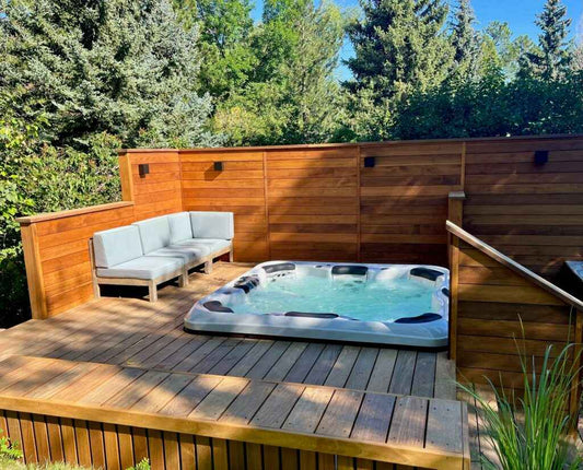 Outdoor hot tub on wooden deck with gray cover and corner bench seating
