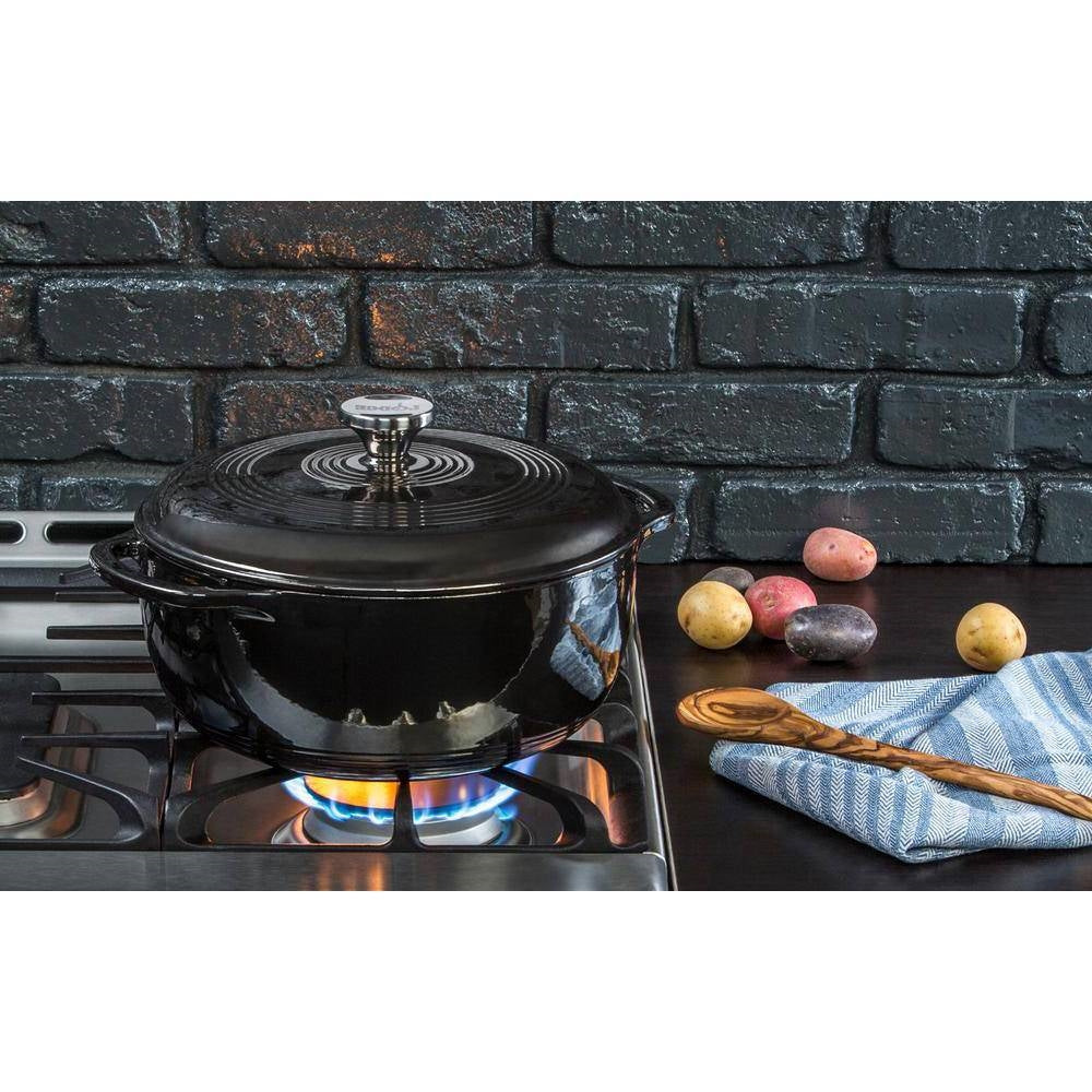 Black enamel cast iron Dutch oven with lid on stovetop, round knob and side handles