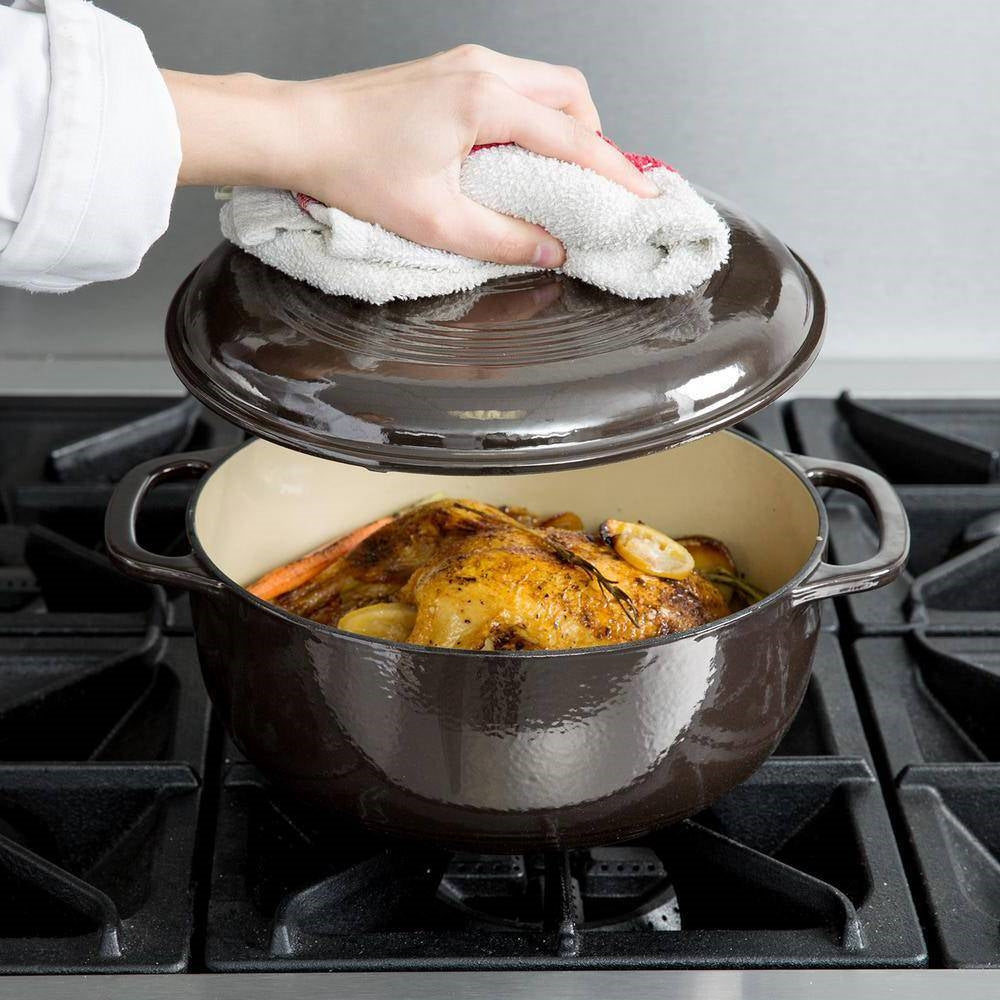 Black enamel cast iron Dutch oven with lid, hand wiping top, side handles