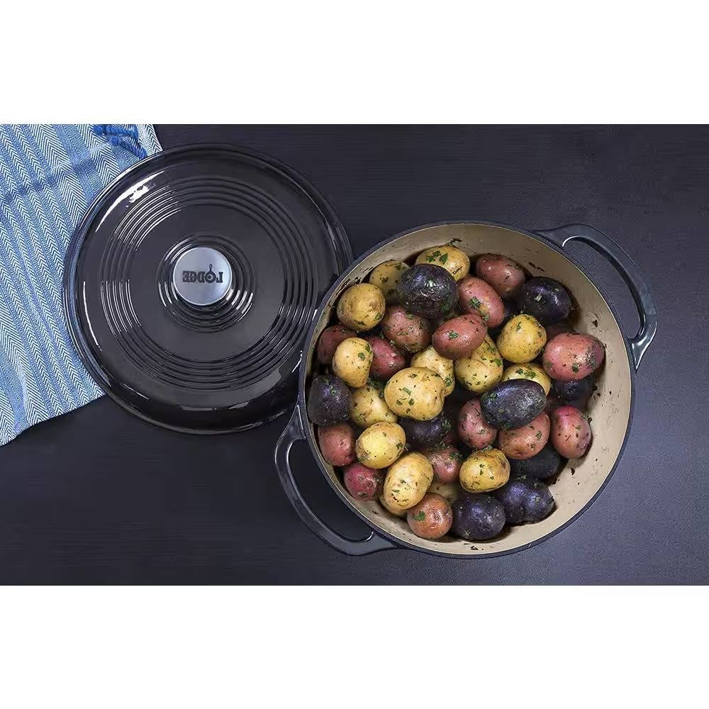 Black enamel cast iron Dutch oven with lid open, beige interior with vegetables and handles