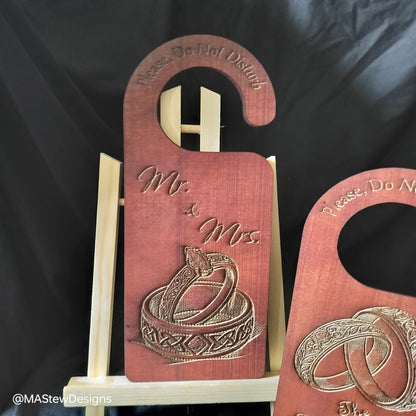 Wooden door hanger with 'Mr. & Mrs.' and wedding rings design on a black background.