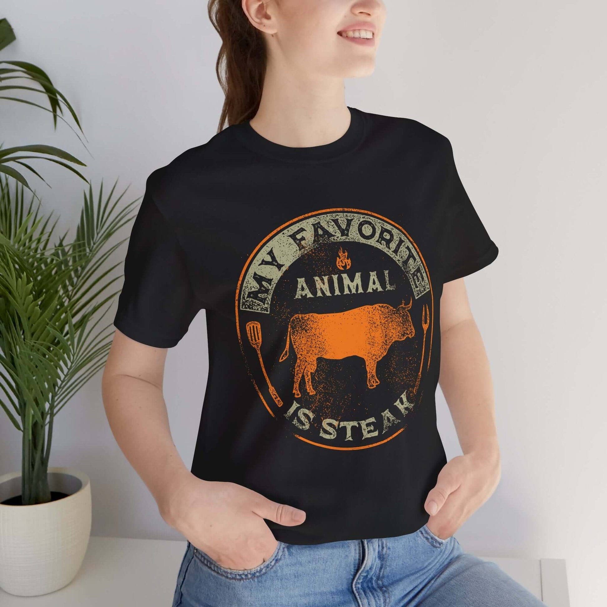 Black T-shirt on model with orange and tan round animal steak logo graphic