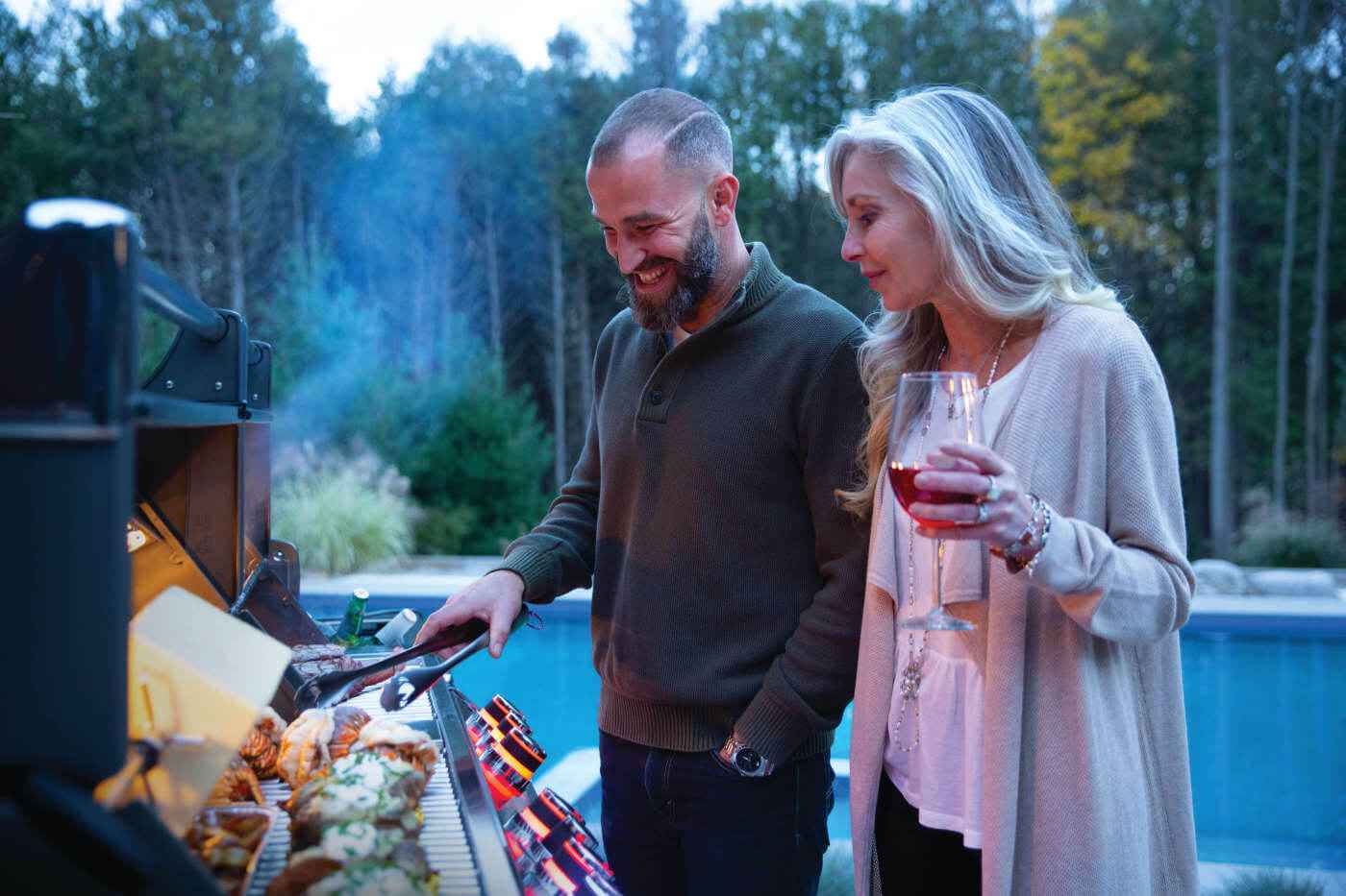 Outdoor gas grill with side burner controls and open cooking area behind the lid