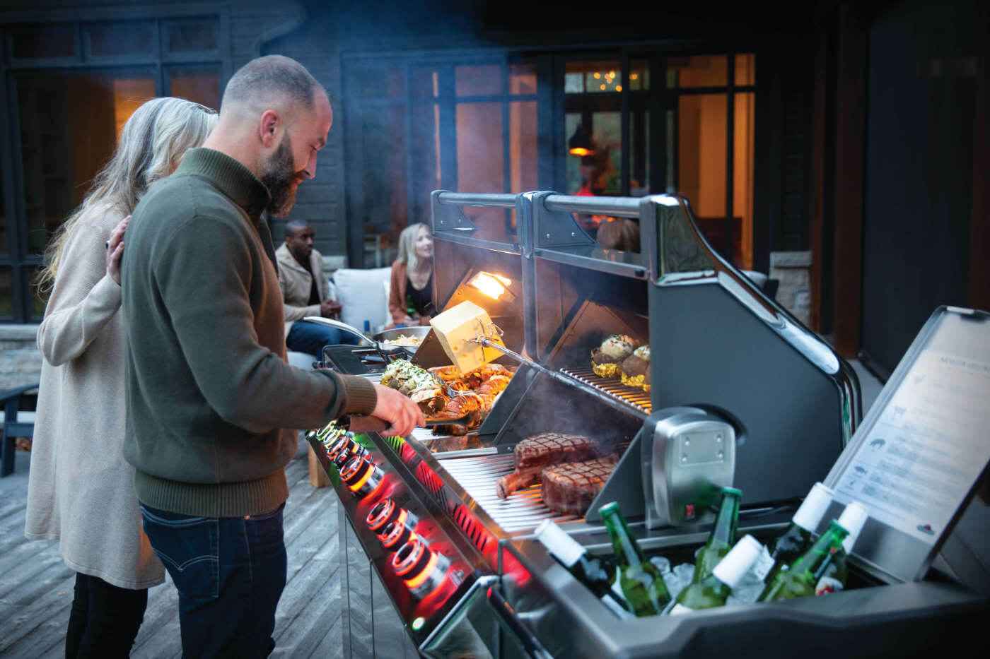 Gas grill with open lid, glowing burners, and food on the cooking grates