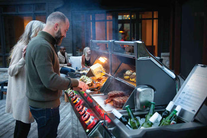 Gas grill with open lid, glowing burners, and food on the cooking grates