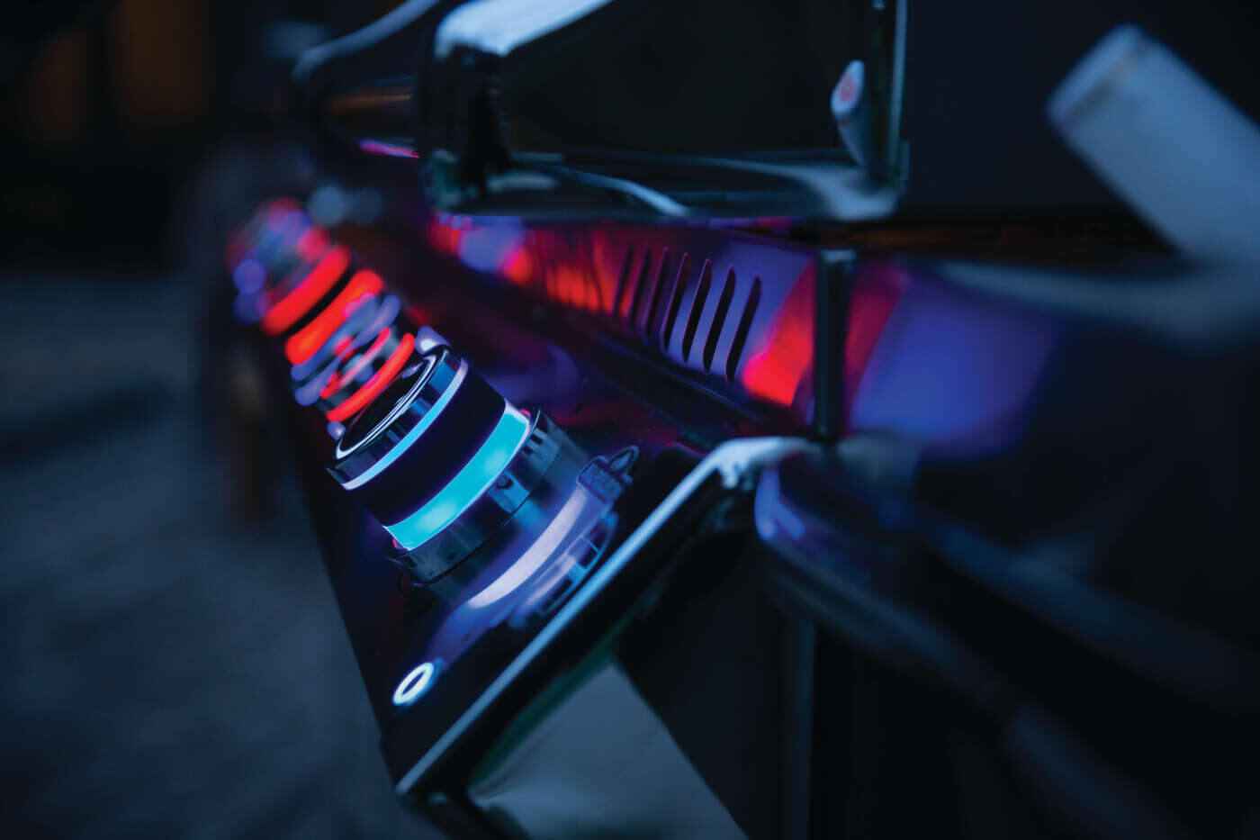 Gas grill close-up with burner flames and glowing red heating elements inside hood