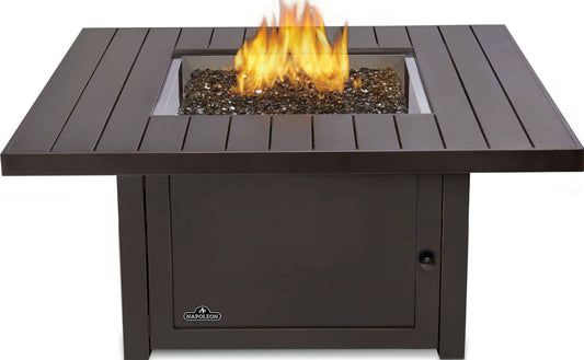 Square outdoor fire table with dark slatted top and visible flames in the burner tray