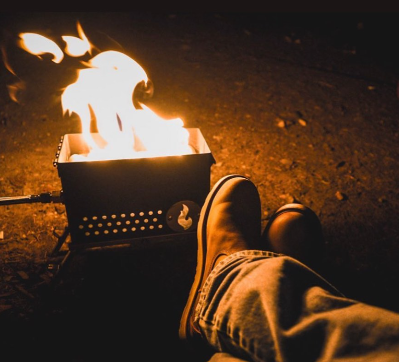 Metal campfire firebox with high flames rising from the cooking basket