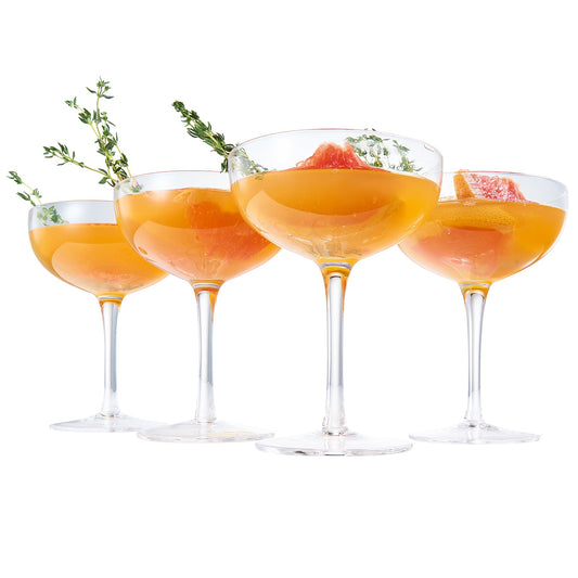 Champagne coupe cocktail glass set of four with orange beverage and citrus garnish