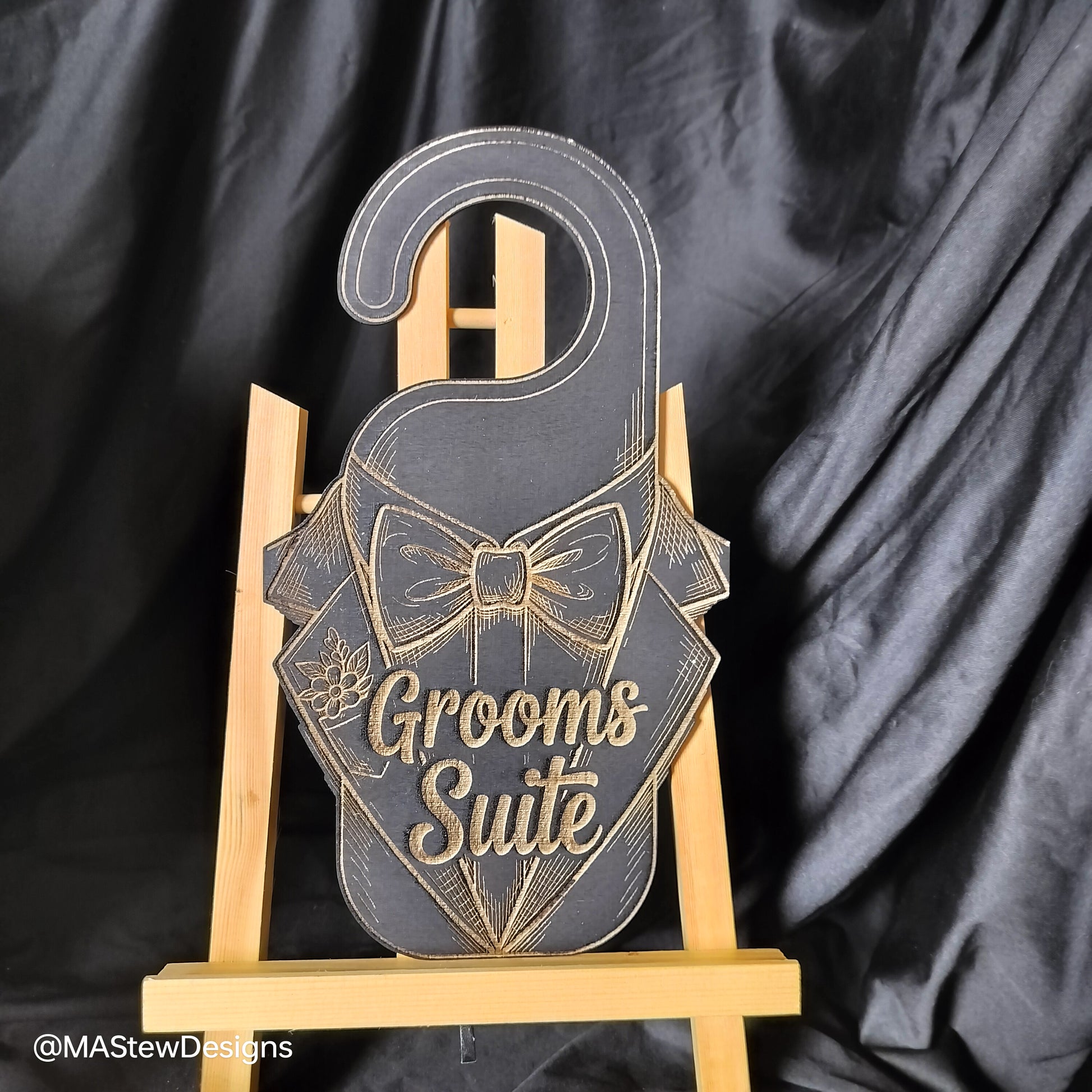 Decorative sign with 'Grooms Suite' text on a stand against a black background