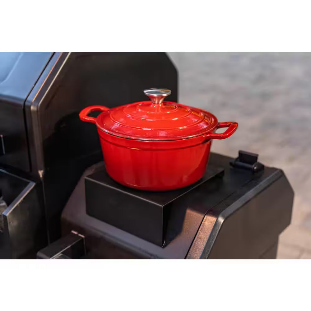 Cast-iron style red Dutch oven on the grill warming surface
