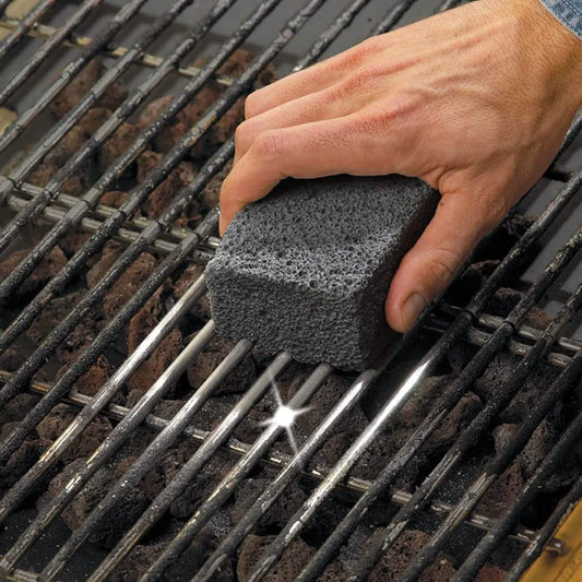 Pumice grill cleaning block rubbed on dark metal BBQ grates for scrubbing