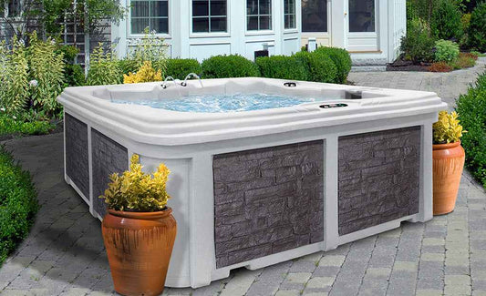 Square outdoor hot tub with white cover and dark stone-look side panels.
