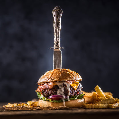 Seasoned burger with cheese, herbs, pickles, and caramelized onion on bun.