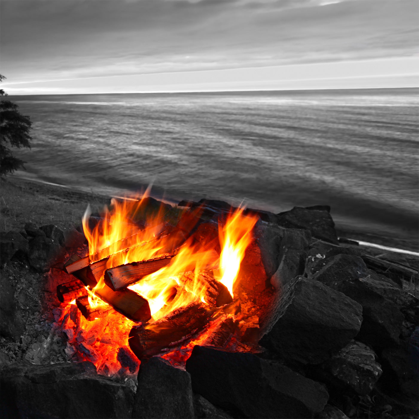 Open fire in a stone pit with bright orange flames and burning logs.