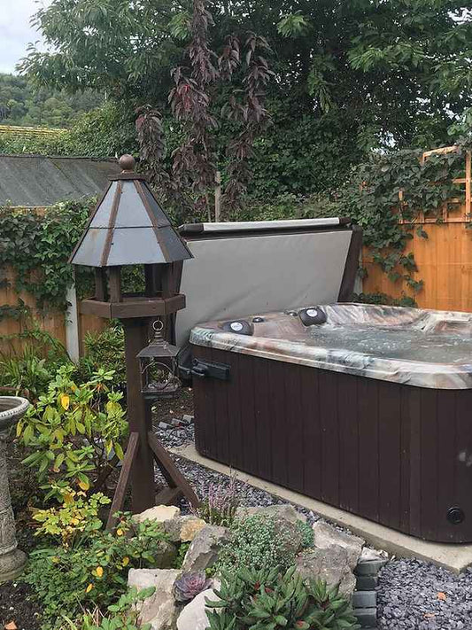 Outdoor 4-person hot tub spa with dark cabinet and open cover