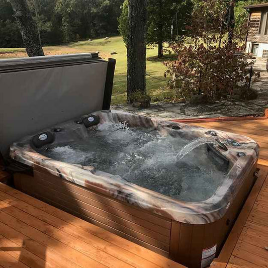 Wood-sided hot tub with clear cover and bubbling water with multiple massage jets