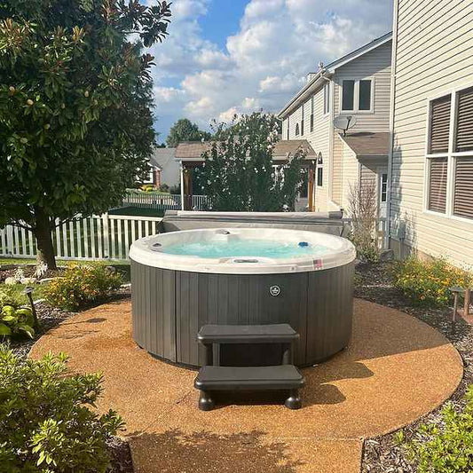 Round outdoor hot tub with gray cabinet and visible interior seats