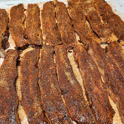 Seasoned beef rub coating with gritty spice texture on meat strips