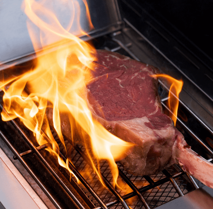 Gas grill cooking grate with steak searing over open flames