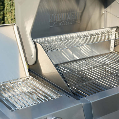 Stainless gas grill with open hood, cooking grates, and warming rack