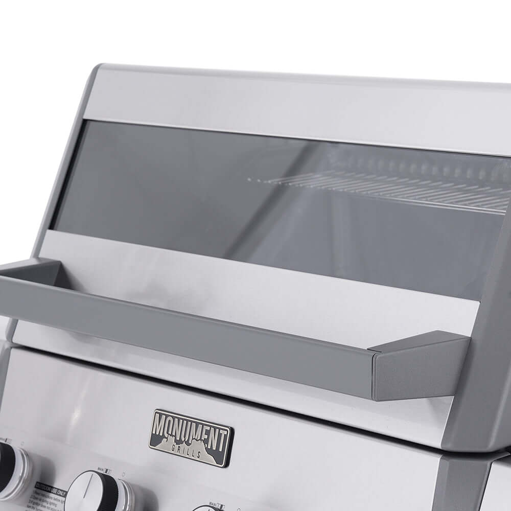 Gas grill lid open with side shelves and Monument label on front panel