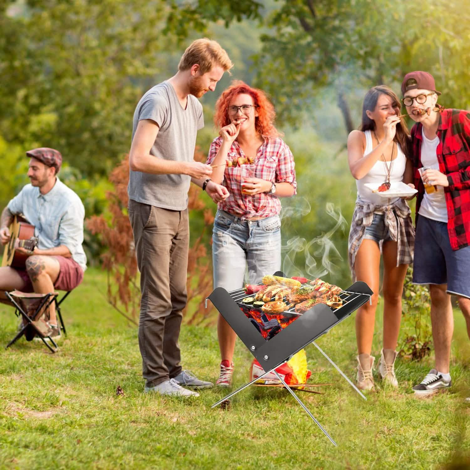 Foldable charcoal BBQ grill on X-shaped metal legs with steel cooking grate, outdoors.