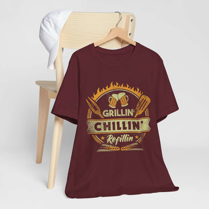 Maroon graphic BBQ T-shirt with grill and chillin’ refillin’ emblem on hanger
