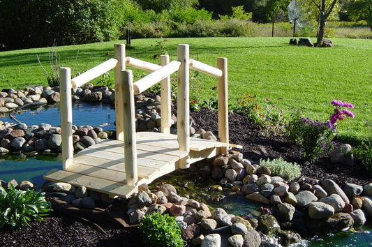 White decorative garden bridge with railings over a small pond