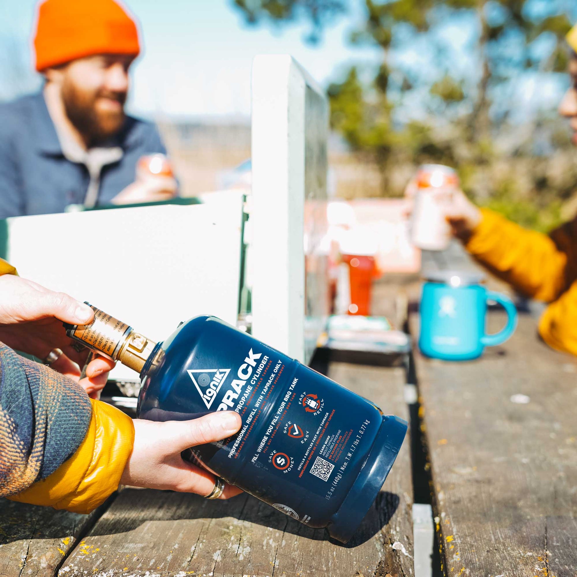 TapRack refillable propane cylinder held outdoors with blue label
