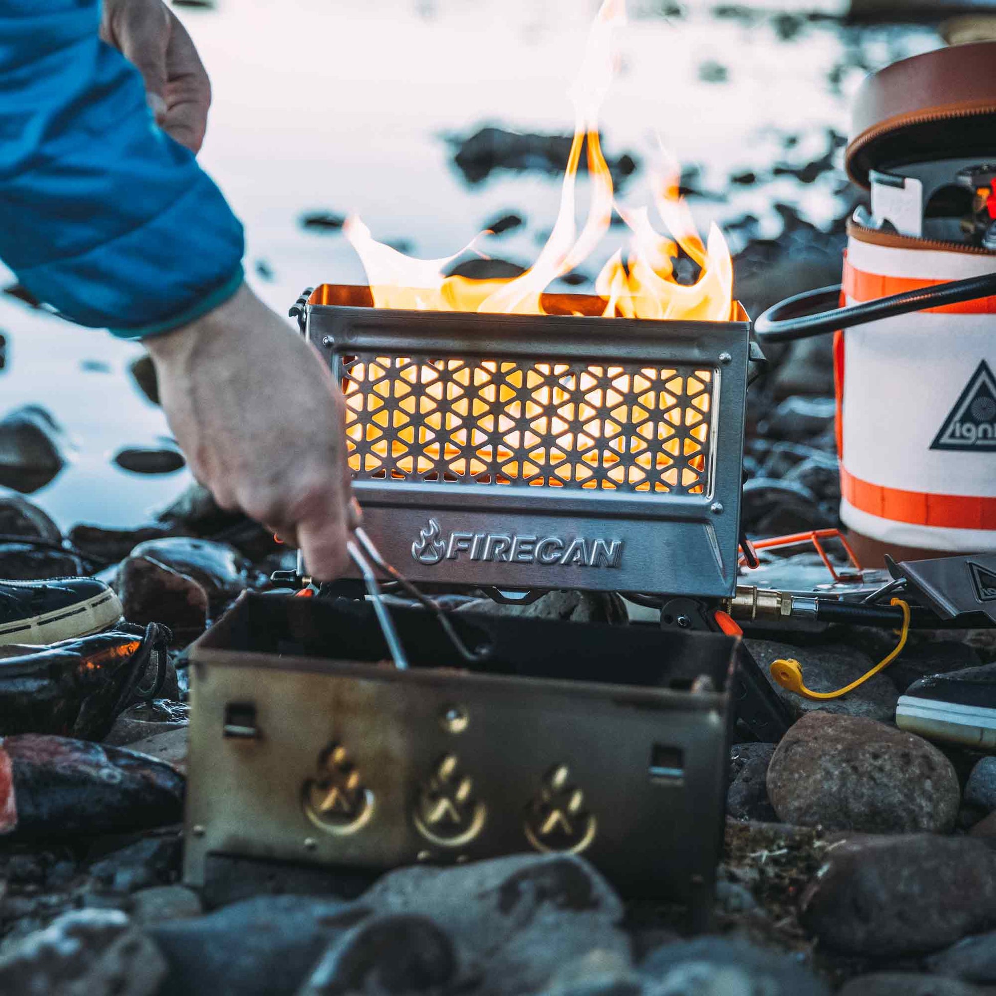 Portable metal fire pit with mesh front panel, flames visible, FIRECAN logo