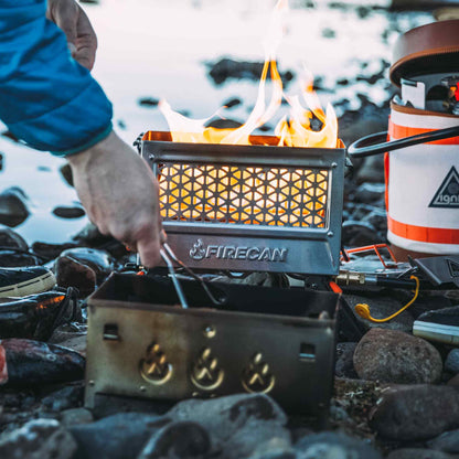 Portable metal fire pit with mesh front panel, flames visible, FIRECAN logo