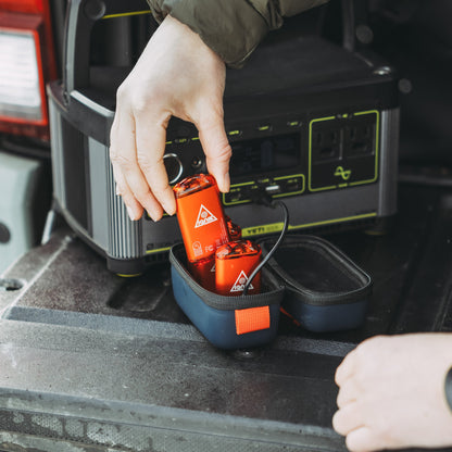 Lava orange hand warmer being placed into a navy carrying pouch