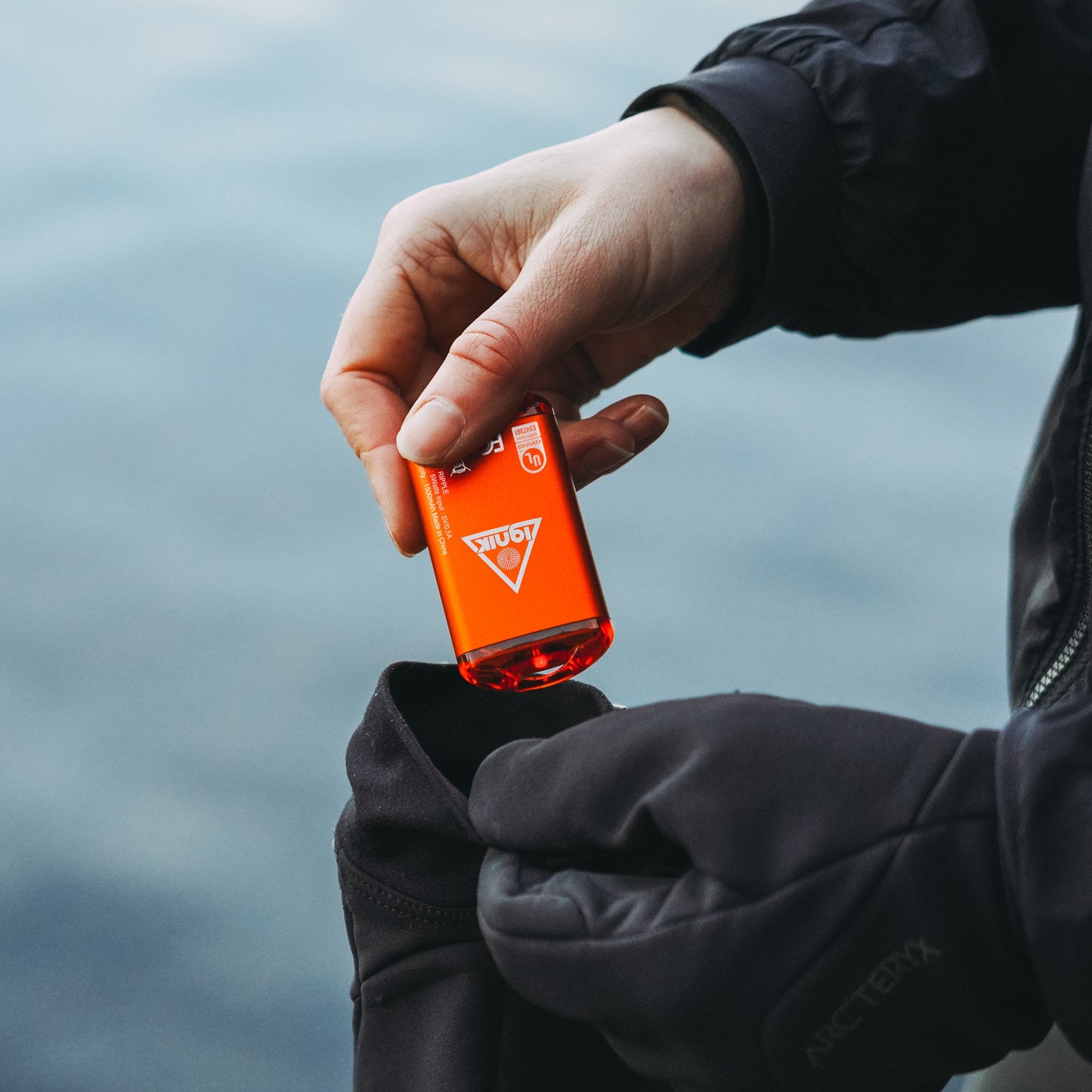 Lava orange rechargeable hand warmer held over a dark pant cuff
