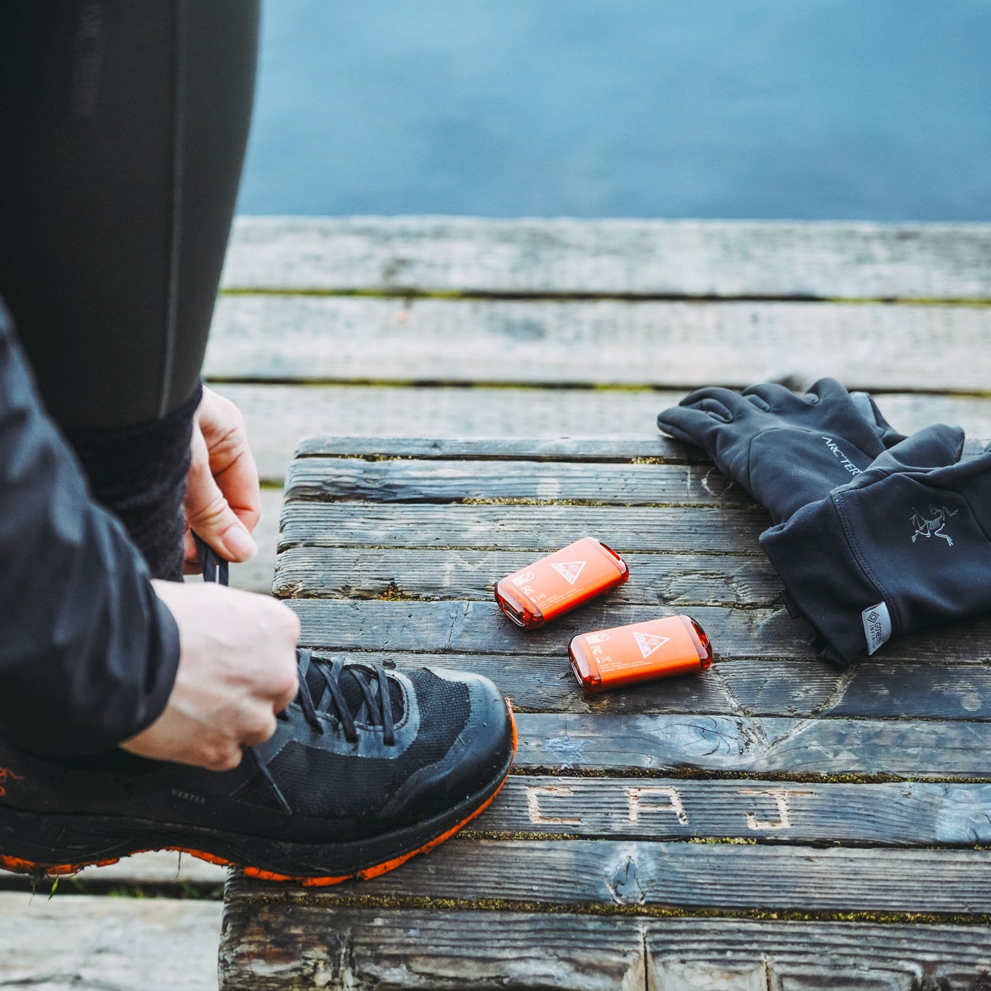 Two lava orange rechargeable hand warmers resting on a wooden bench