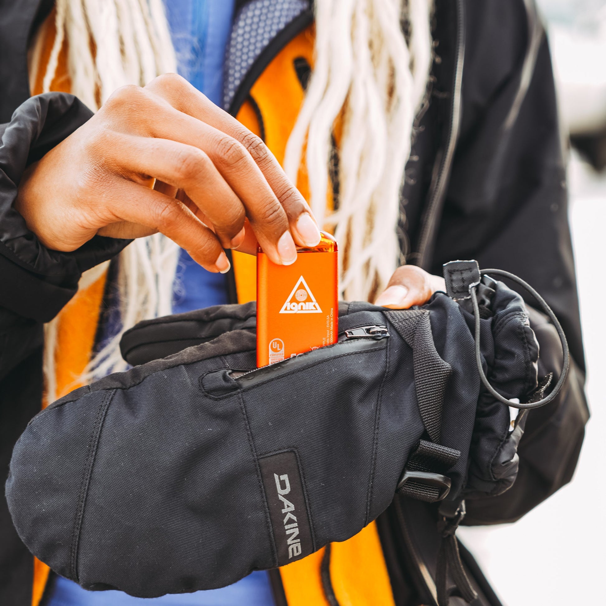 Lava orange rechargeable hand warmer clipped inside a dark glove pocket