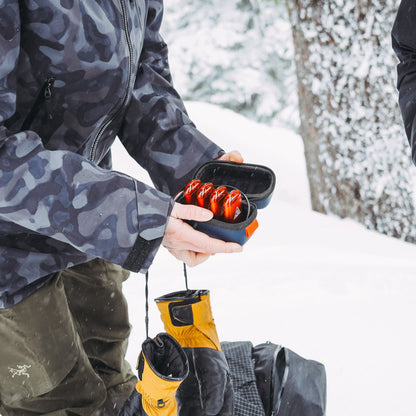 Lava orange rechargeable hand warmers inside a zippered black travel case