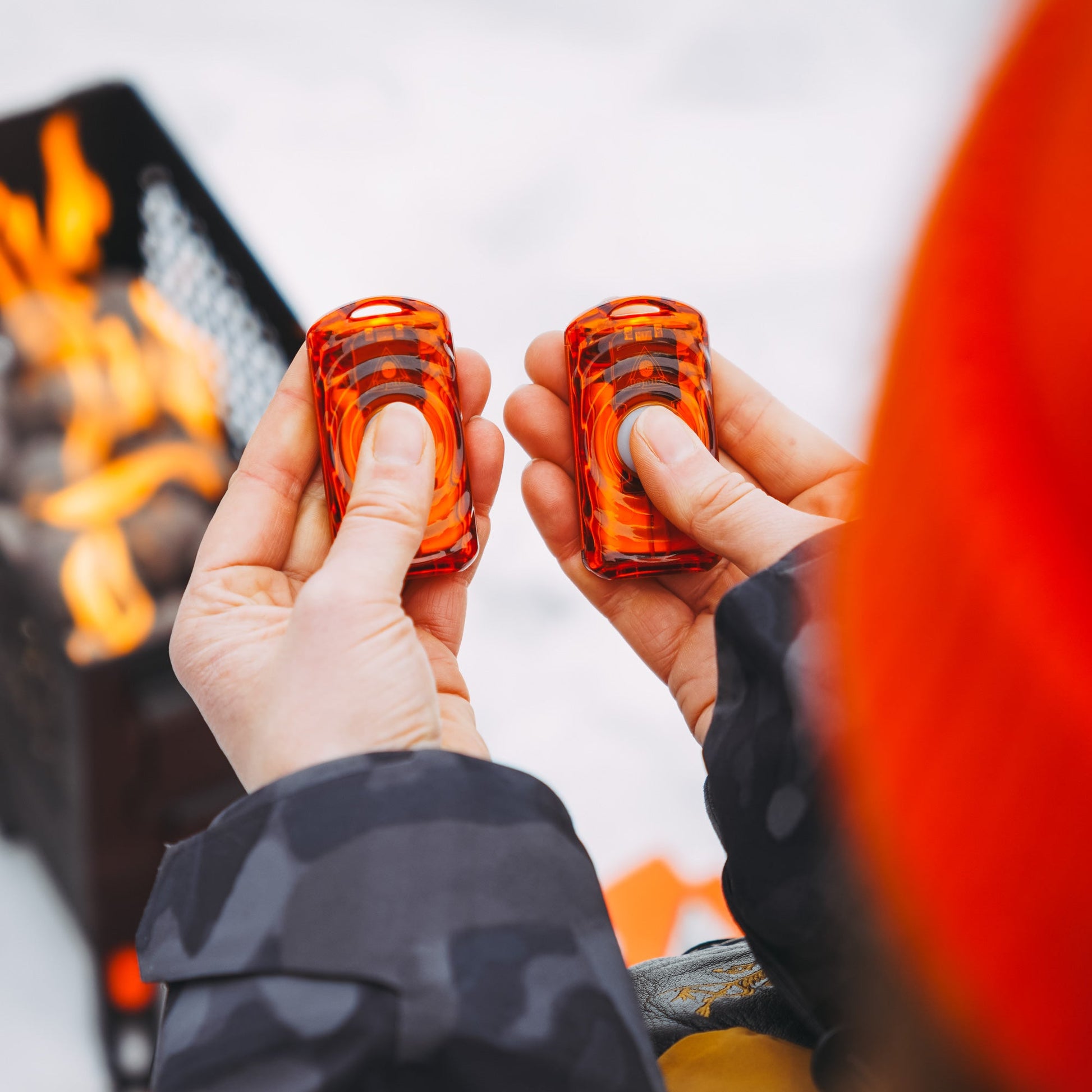 Lava orange rechargeable hand warmers held in hands, clear top cylinder design