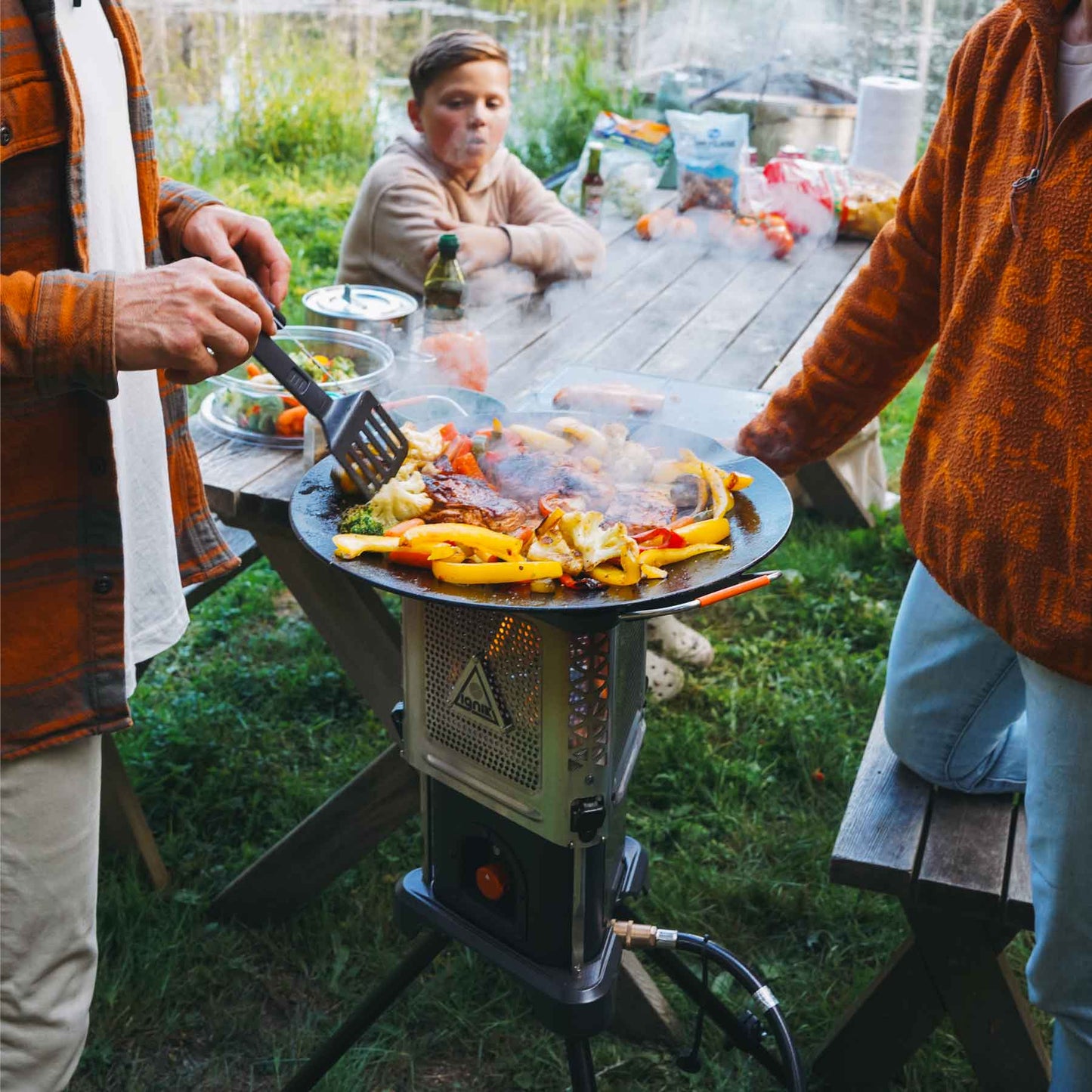 Outdoor heater stove cook set with skillet on burner, grilling food with visible steam