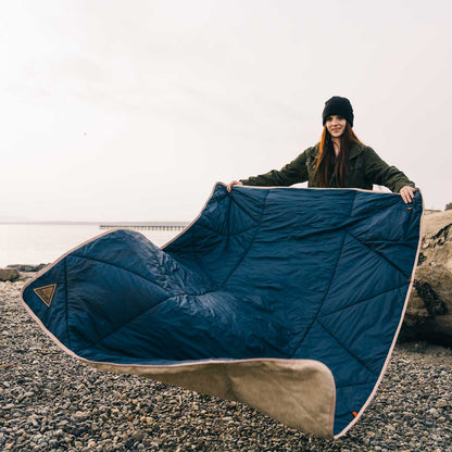 Blue heated blanket spread outdoors with tan edge trim and attached power cable