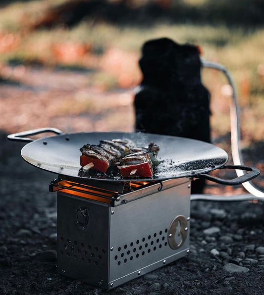 Outdoor campfire grill station with round skillet and grilling surface, food being cooked