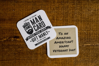 Two Man Card gift cards on wooden surface, one shows “When you gift…”, the other text.