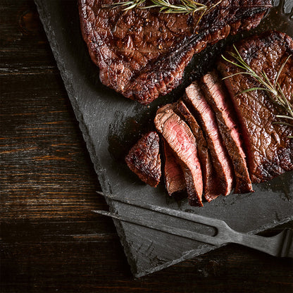 Spice-rubbed pork chops on a dark board with rosemary sprigs