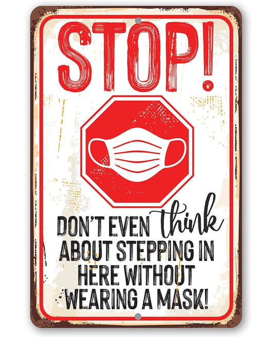 Red STOP metal sign with mask icon and warning text, dark border frame.