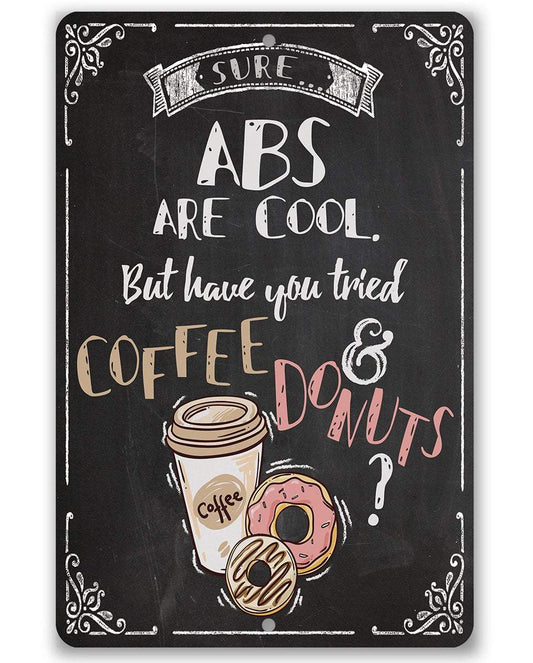 Black metal sign with “ABS are cool” text, coffee cup and donut graphic, decorative border.