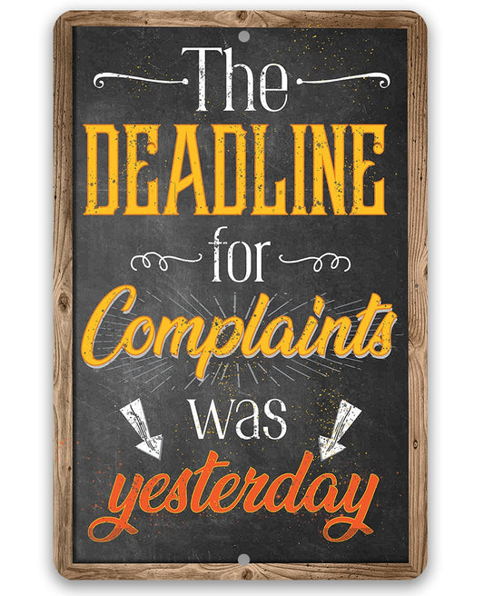 Metal sign with dark chalkboard-style center, wooden frame, and colorful complaint deadline text