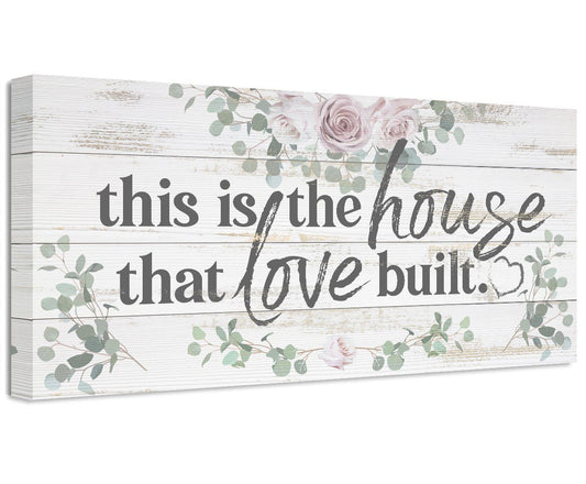 Stretched canvas wall art with floral wreath and script text: this is the house that love built